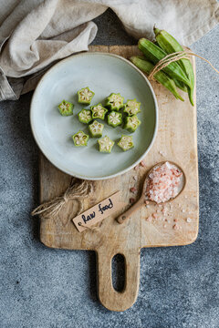 Fresh bamia displayed with salt and raw food tag on wooden board