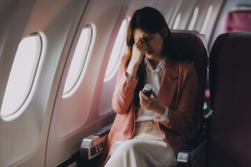 Fototapeta premium Tired asian woman with headache feeling sick while sitting in the airplane , Passengers near the window.
