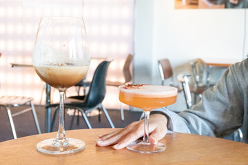 Glass of Cold Orange Mocktail on table,female hand swirling red wine in wine glass,Friends cheering with wineglasses.