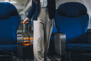 Businesswoman, confident tourist walks with suitcase, checks seat, flight number, puts her suitcase on shelf inside airplane travel lifestyle concept.