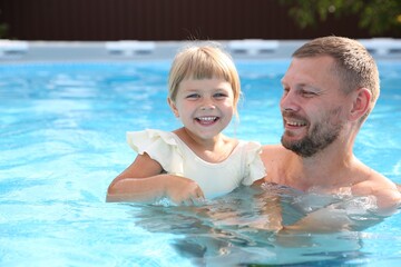 Fototapeta premium Happy father having fun with his daughter in swimming pool