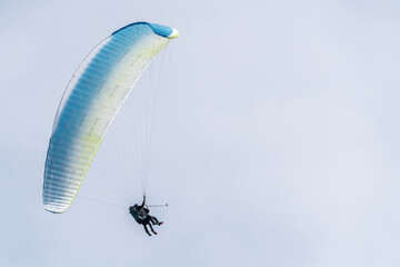 A blue and white paraglider flying in the sky
