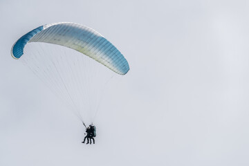 A blue and white paraglider flying in the sky