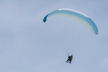 A blue and white paraglider flying in the sky