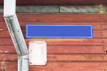 Old wooden house close-up with street name and number sign. Metal gutter and wooden plank exterior. Rustic architecture and vintage charm. Empty copy space blank street name.