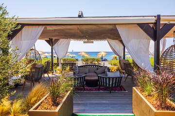 Obraz premium Beautiful view of standalone canopy with rattan furniture on Mediterranean beach on the island of Crete.