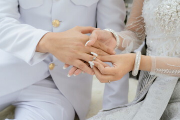 groom wears ring on bride's finger in wedding ceremony