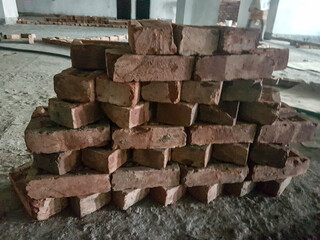 5 August 2024 Dhaka, Bangladesh. The image shows a pile of red bricks in a room. The bricks are stacked in a pyramid shape.