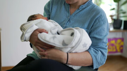 Mother holding newborn baby, close-up arms holding infant during the initial days of life of infant