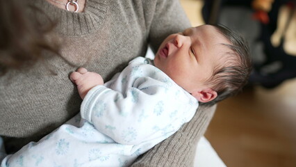 Newborn baby being held in arms during the first days of life. infant child's initial week of life seen from above close-up