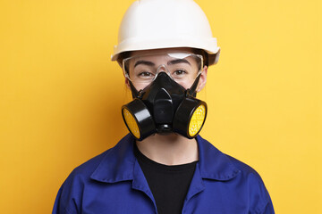 Worker in respirator, protective glasses and helmet on orange background