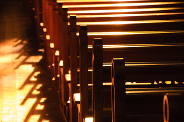 
Rows of church benches. Sunlight filtered through the stained glass window. Selective focus. Religious background. Divine light, grace, hope, miracle concepts