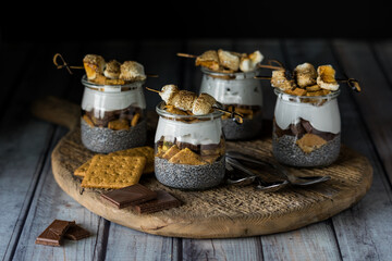 Smores chia puddings on a wooden board against a dark background.