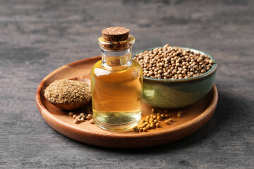 Coriander essential oil, seeds and powder on grey table