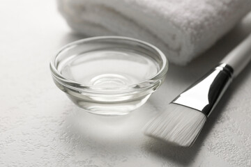 Peeling procedure. Chemical peel liquid in bowl, towel and brush on white table, closeup