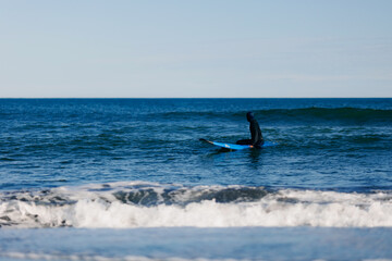Fototapeta premium Man with surfboard in wetsuit going to surf in winter ocean Kamchatka Russia