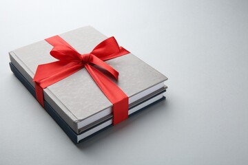 Books tied with red ribbon on grey background, closeup. Perfect gift