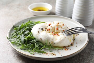 Delicious burrata cheese, arugula and spices on grey table, closeup