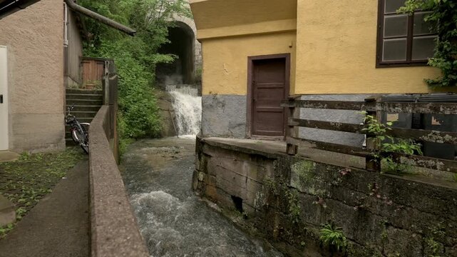A narrow alleyway in Hallstatt, Austria, featuring a flowing stream and rustic buildings, creating a quaint and charming scene. High quality 4k footage