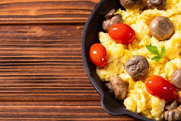 Healthy vegetarian breakfast . Scrambled eggs in pan with cherry tomatoes and parsley