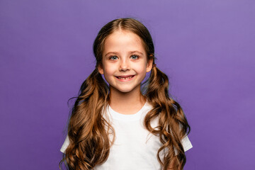 T-shirt design concept - smiling happy little girl in blank white t-shirt on a purple background. Portrait of nice-looking, lovely, attractive, curious, creative cheery long-haired girl, copy space