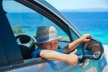 Naklejka premium A happy child in a car by the sea in nature weekend travel