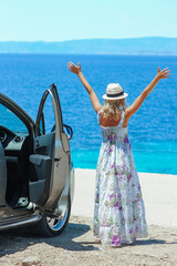 A happy girl with a car near the sea in nature weekend travel