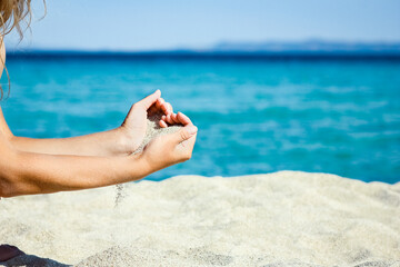 A hands pouring sand near the seashore on weekend nature travel