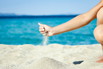 A hands pouring sand near the seashore on weekend nature travel