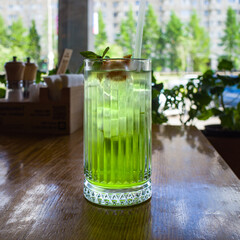 green basil lemonade chilled against the background of the interior and the window of the restaurant