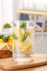 Freshly made lemonade with mint in jug on wooden table indoors