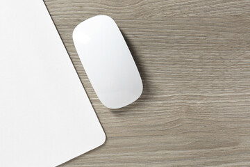 Wireless mouse and mousepad on wooden table, top view. Space for text