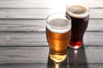 Glasses with different types of beer on grey wooden table, space for text