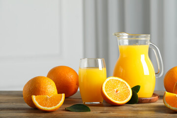 Tasty orange juice, green leaves and fresh fruits on wooden table