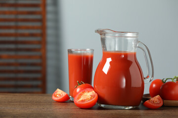 Tasty tomato juice in jug, glass and vegetables on wooden table. Space for text