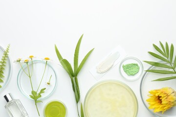Petri dishes with green leaves, flowers and cosmetic products on white background, flat lay