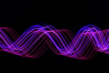 Long exposure photograph - Light Painting Photography - swirly waves of neon pink purple light against a black background