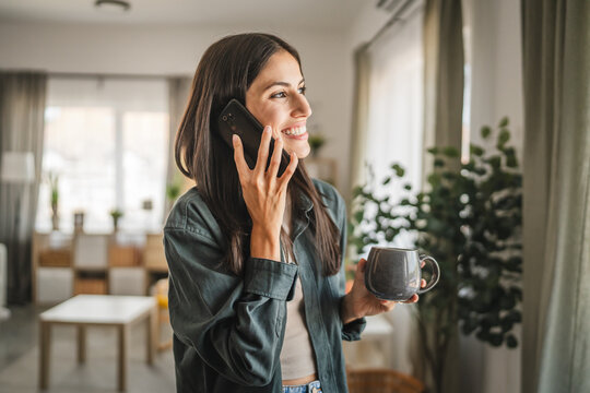 Portrait of adult young woman stand hold cup and talk on mobile phone