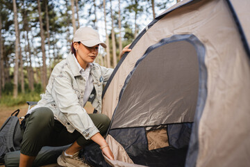 Young woman set up a tent in nature ready for camping in the forest