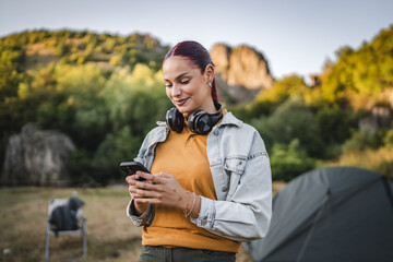 portrait of young woman with headphones stand and use cellphone