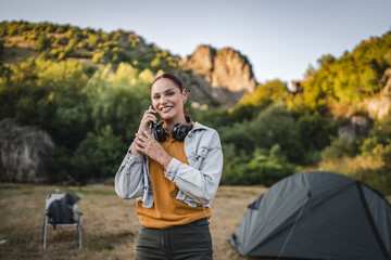 portrait of young woman with headphones stand and talk on mobile phone