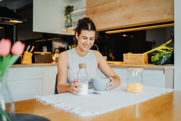 Young caucasian woman eating corn flakes for breakfast at home