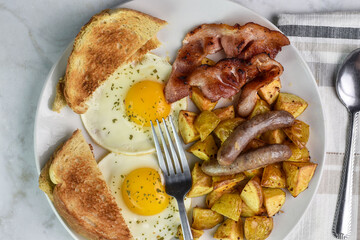 fried eggs served   bacon and sausages  and home fries