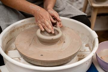 Wheel throwing. Learning how to model clay into different shapes with pottery wheel. Creating a ceramic bowl by yourself in a pottery class.