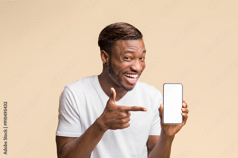 Aufkleber afro man pointing finger at smartphone with blank screen in hand smiling at camera standing over yel