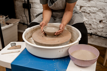 Wheel throwing. Learning how to model clay into different shapes with pottery wheel. Creating a ceramic bowl by yourself in a pottery class.