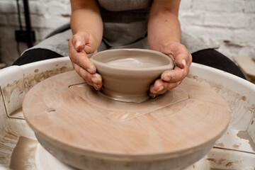 Creating a ceramic bowl by yourself in a pottery class. Wheel throwing. Learning how to model clay into different shapes with pottery wheel.