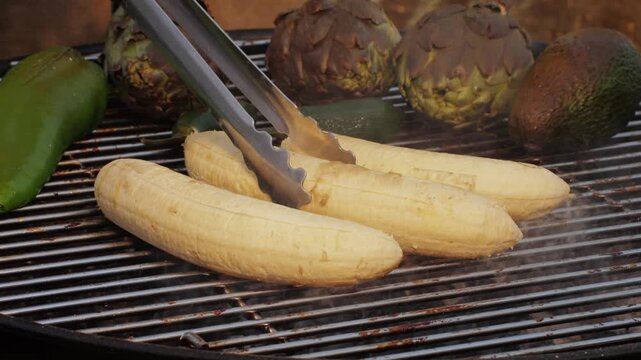 Grilled Banana on fire, latin american vegan grill with avocado and pepper, thai or Ecuadorian Street food. African traditional food on grill. 
