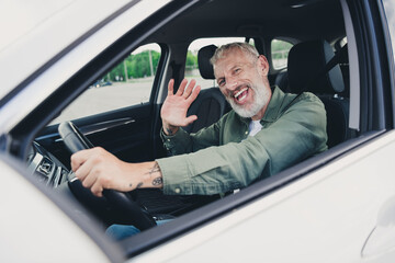 Photo of funky cool mature guy dressed casual shirt waving you hi driving auto outdoors urban car...