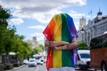 Wrapped In A Rainbow Flag person wrapped in a rainbow flag standing on the city